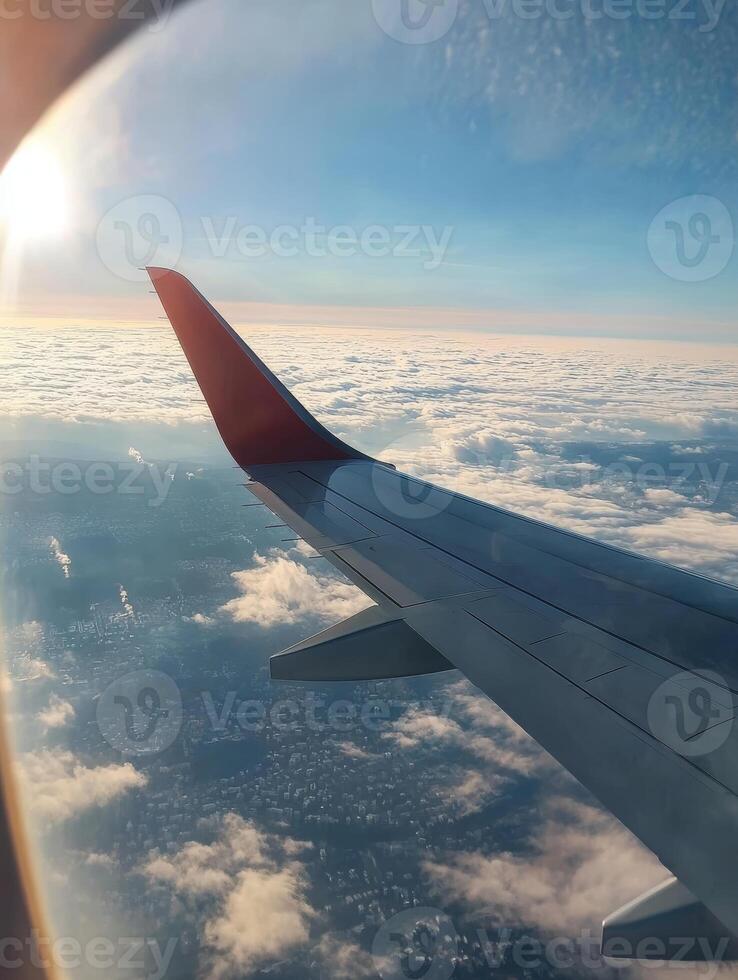 Experience the stunning panoramic view from a commercial airline wing on a serene morning flight, basking in sunlight above fluffy clouds, with a sprawling city skyline majestically below photo