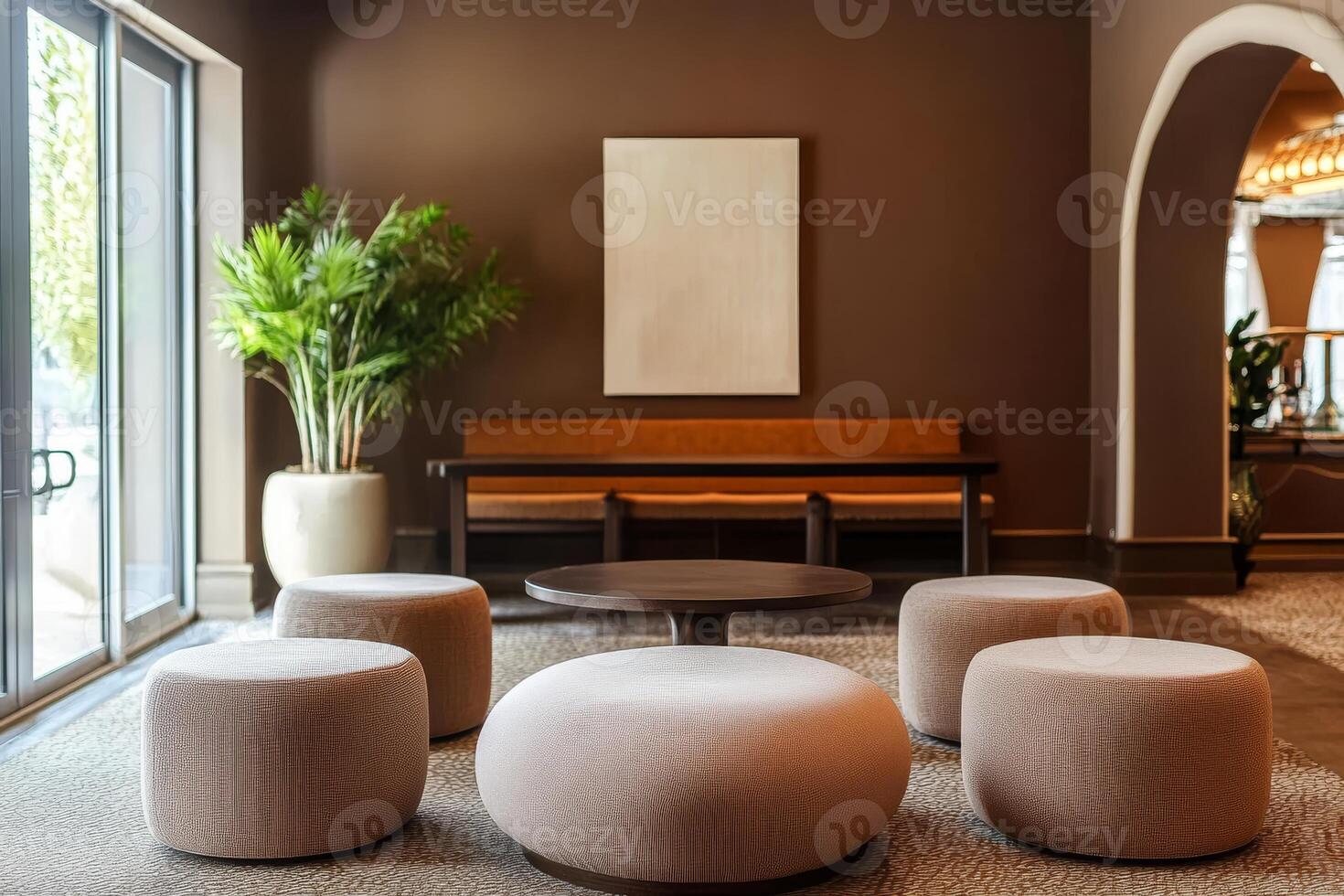 The lobbys chic warm mocha tones, along with the plush ottomans, modern table, and elegant decor, all come together to create a cozy and inviting atmosphere that welcomes guests comfortably photo
