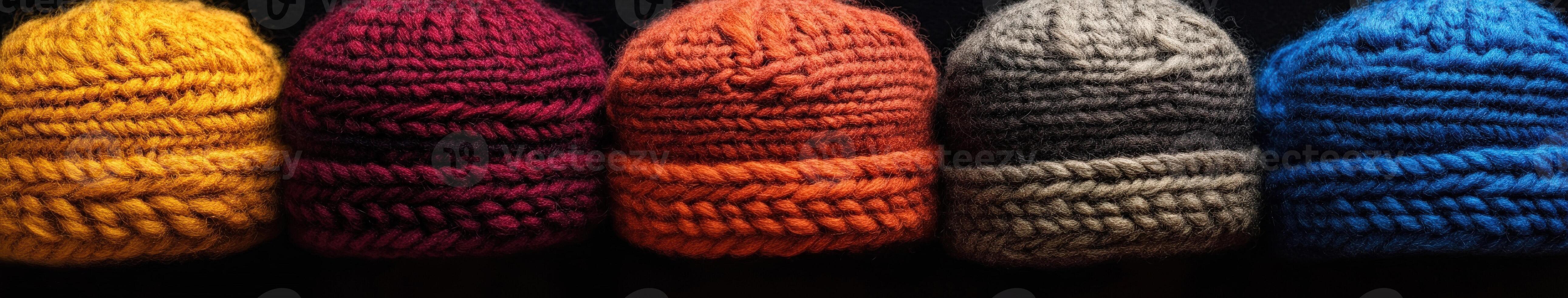 Colorful knitted hats arranged in a row on a dark background photo