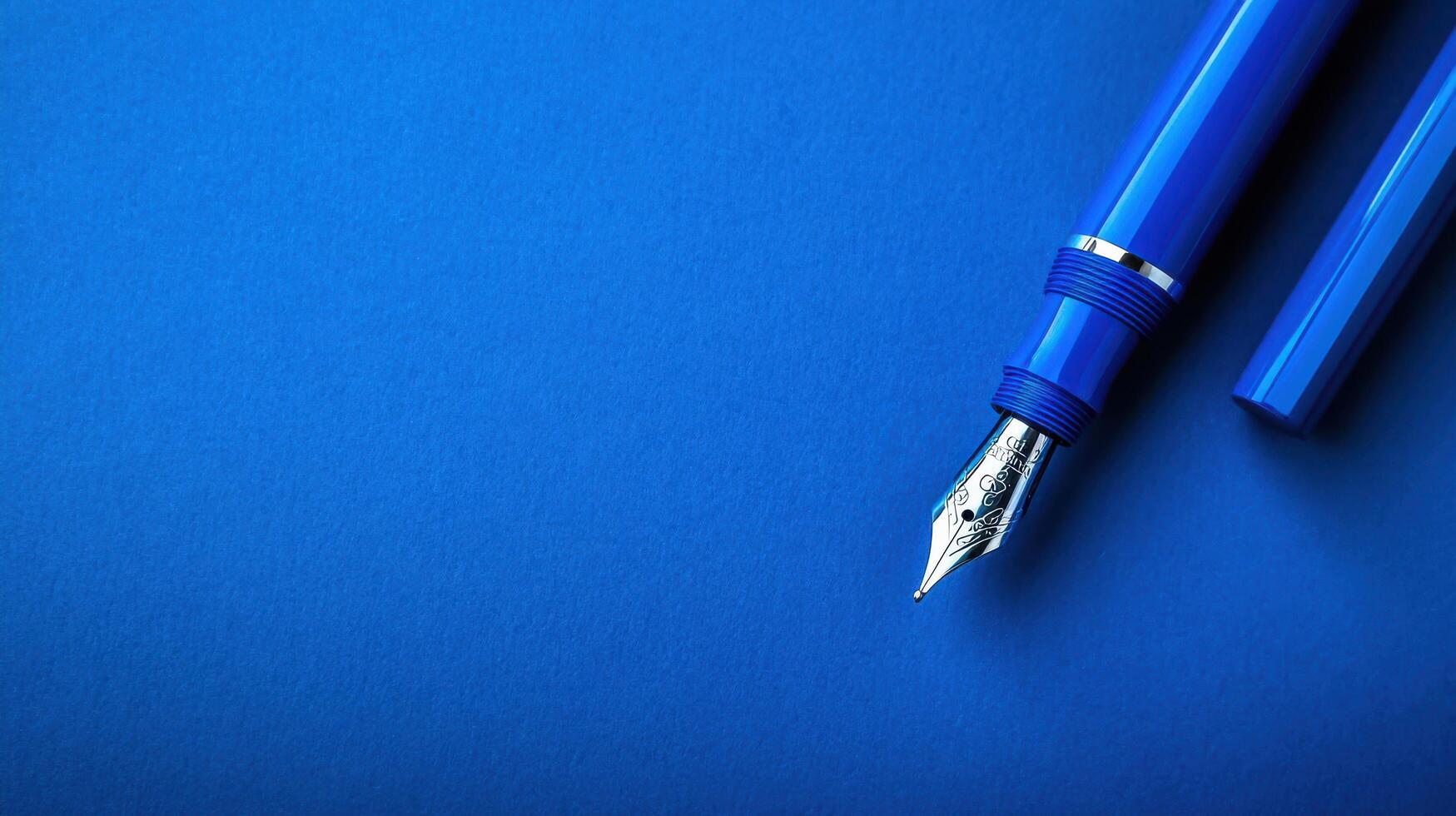 Elegant blue fountain pen on a vibrant blue background showcasing artistry and craftsmanship in writing instruments photo