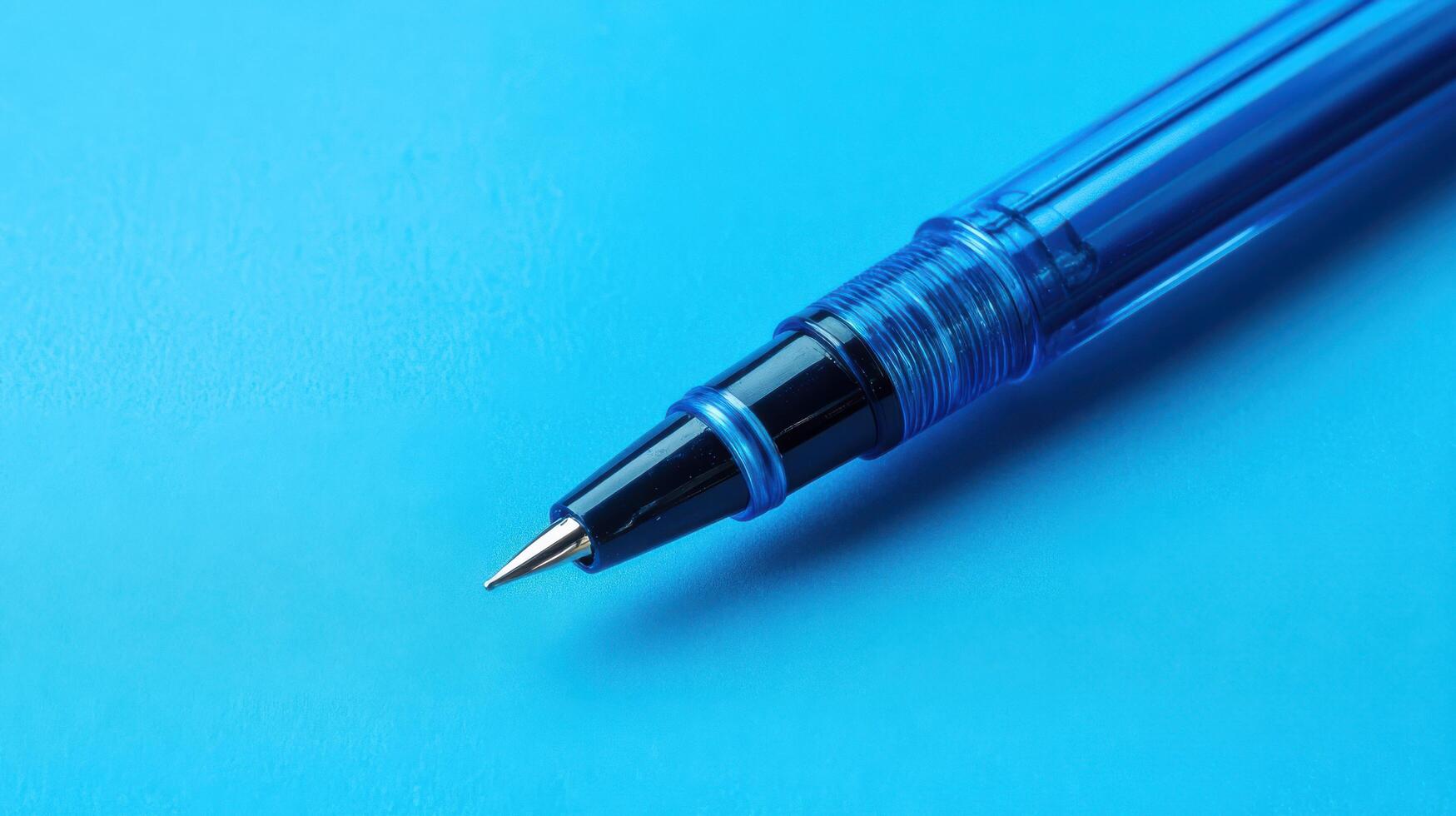 Close-up view of a blue pen resting on a turquoise background showcasing detailed design and fine tip photo