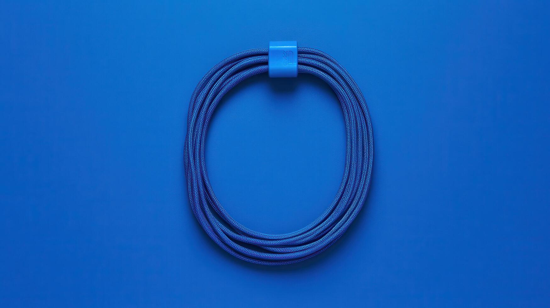 Blue rope coil with a clip displayed on a solid blue background representing simplicity and minimalist design photo