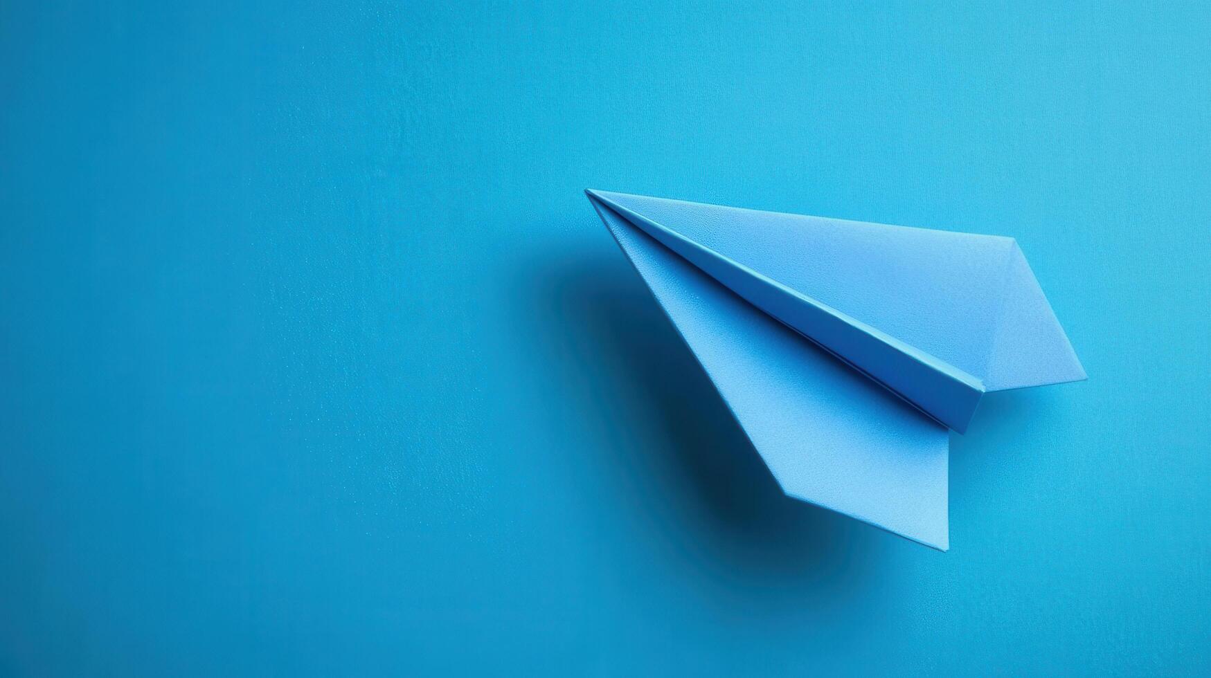 Blue paper airplane resting on a bright blue surface showcasing creativity and simplicity in design and origami craft photo