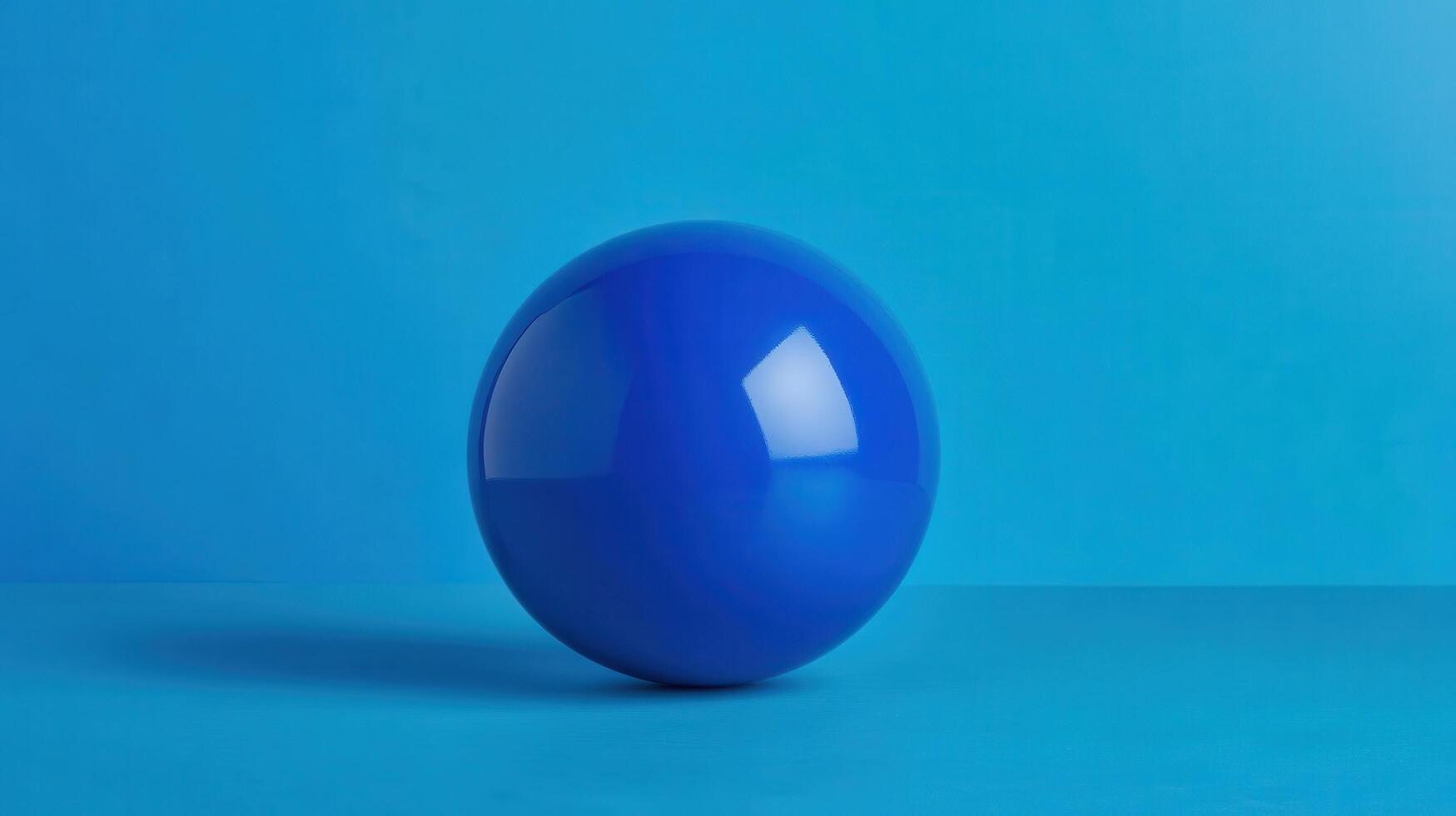 Bright blue glossy sphere sitting on a turquoise surface with a smooth texture in a minimalist setting photo