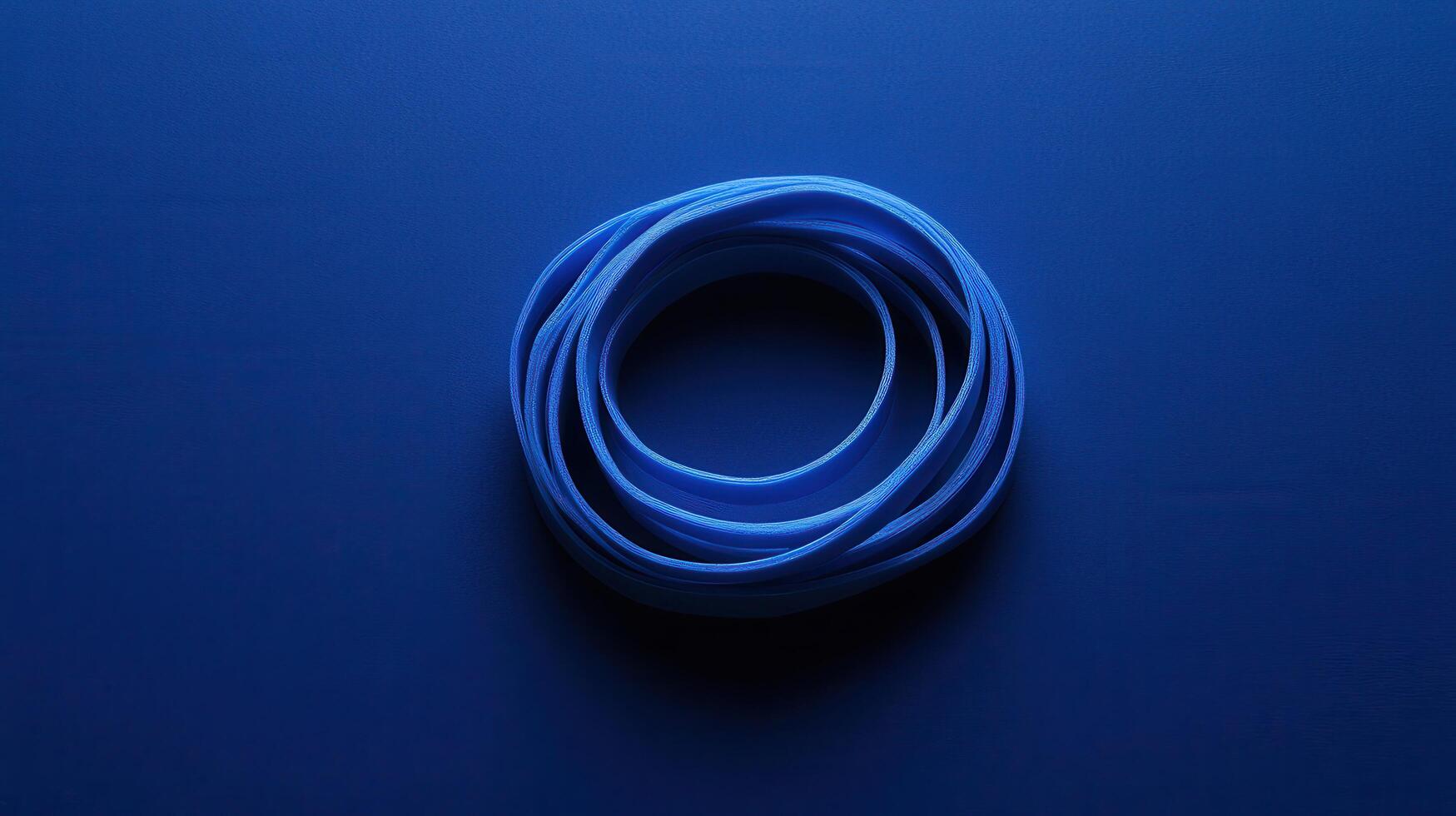 Blue elastic band resting on a deep blue surface captures simple everyday object in striking contrast and calmness photo