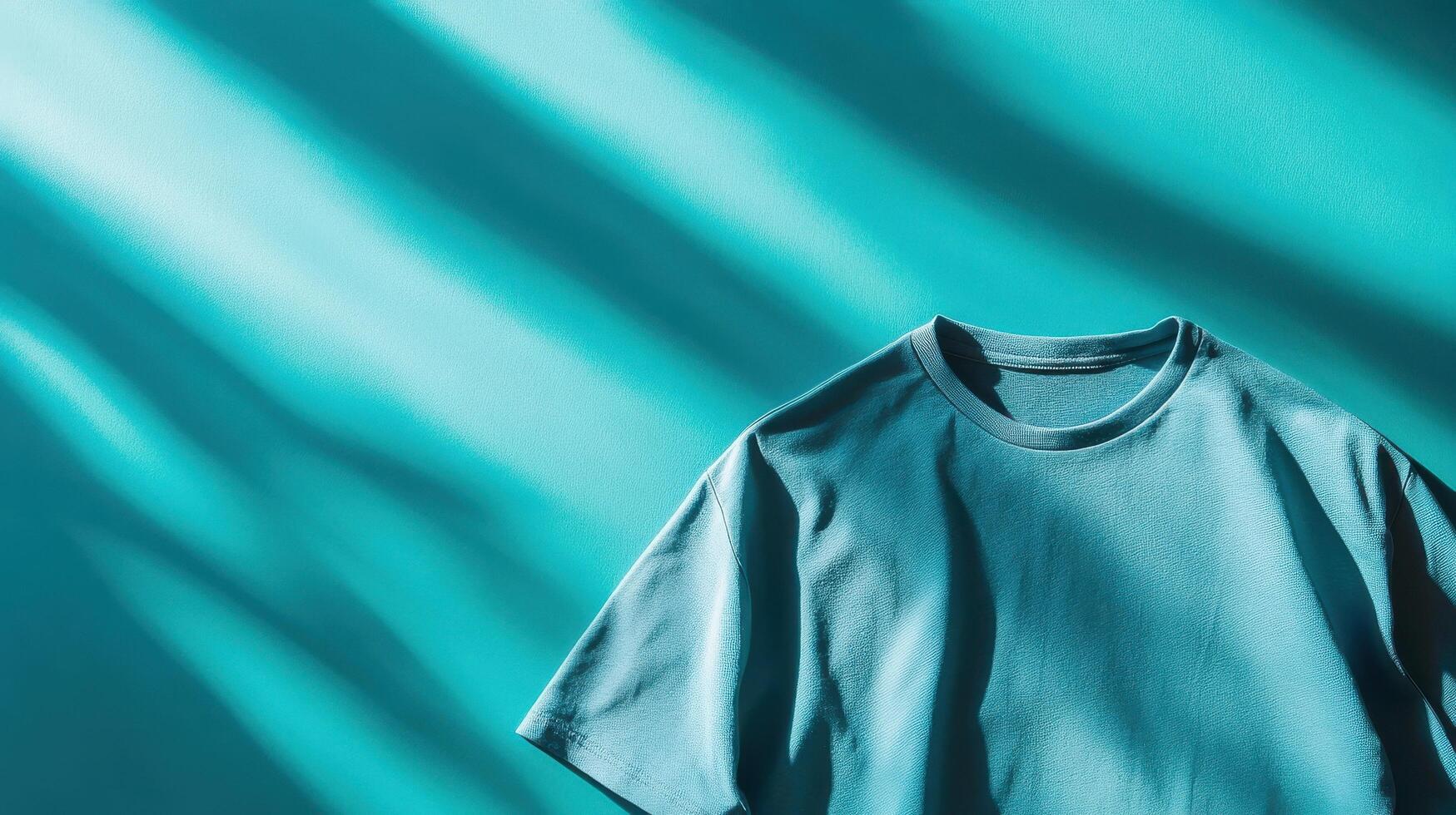Soft teal t-shirt resting on a vibrant background with dynamic shadows created by light photo