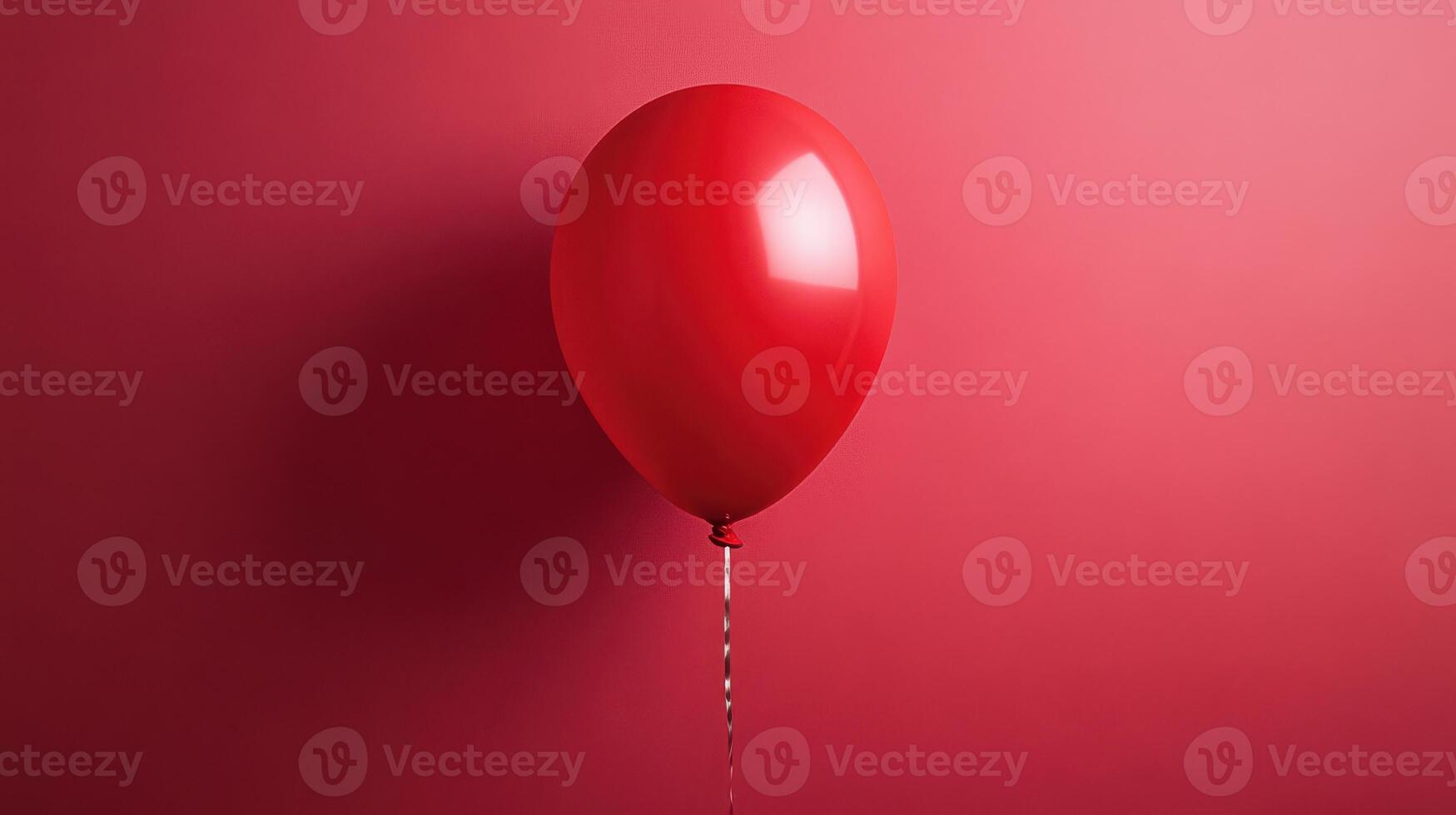 Bright red balloon floating against a vibrant pink wall emphasizing simplicity and color in a minimalist setting photo
