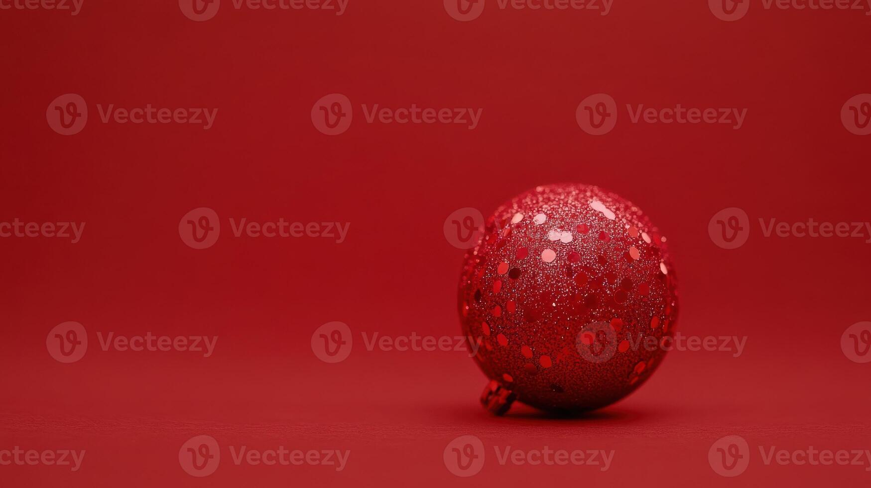 Sparkling red ornament resting on a solid red background creates a festive atmosphere for the holiday season photo
