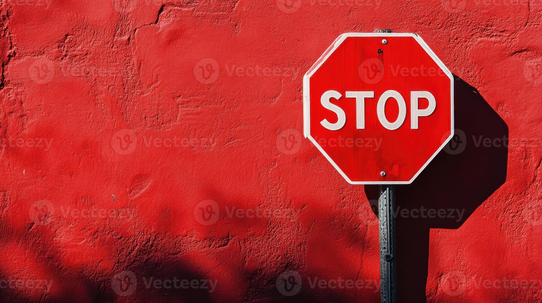 Bright stop sign against a vivid red wall captures attention in an urban setting during daylight hours photo