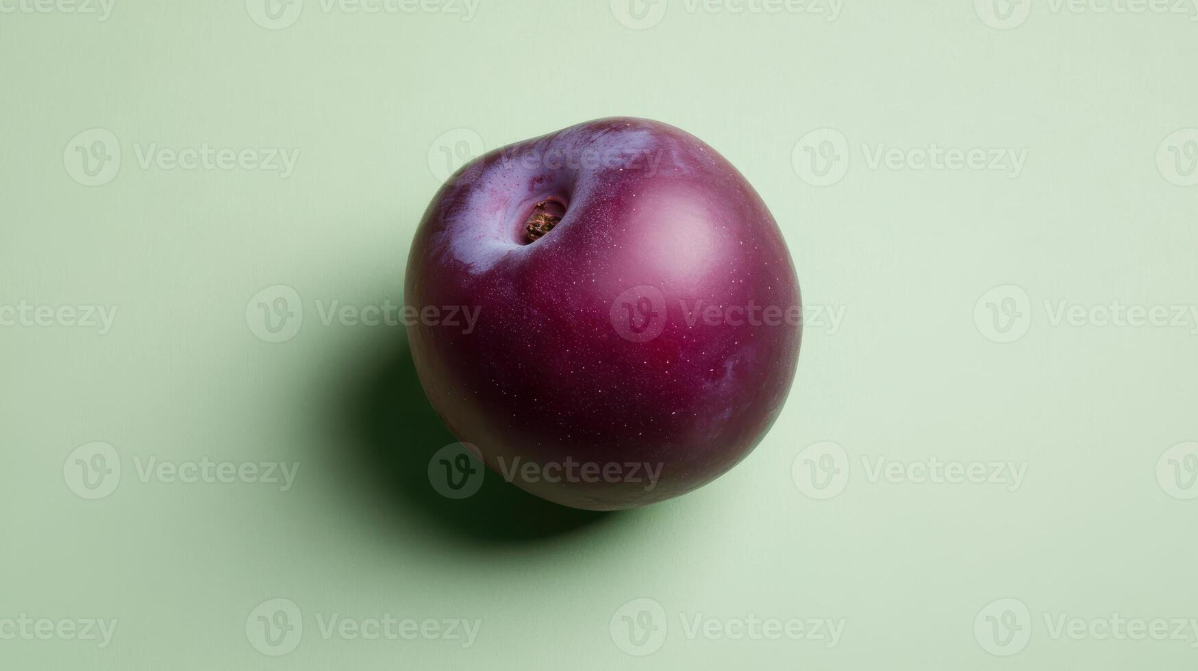 Fresh plum resting on a light green background showcasing its natural shine and color photo