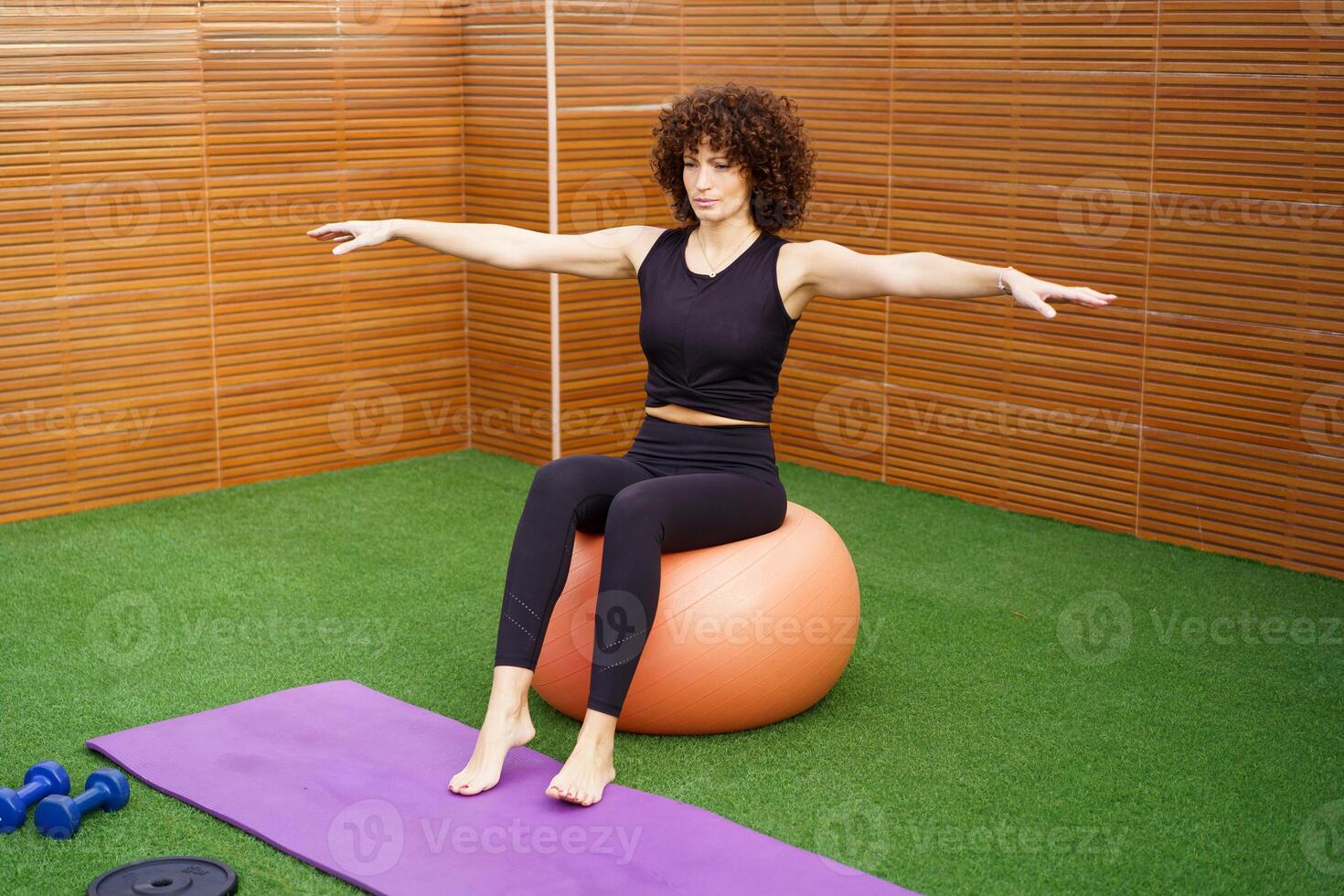 A woman is exercising on a stability ball within a modern gym setting that is wellequipped photo