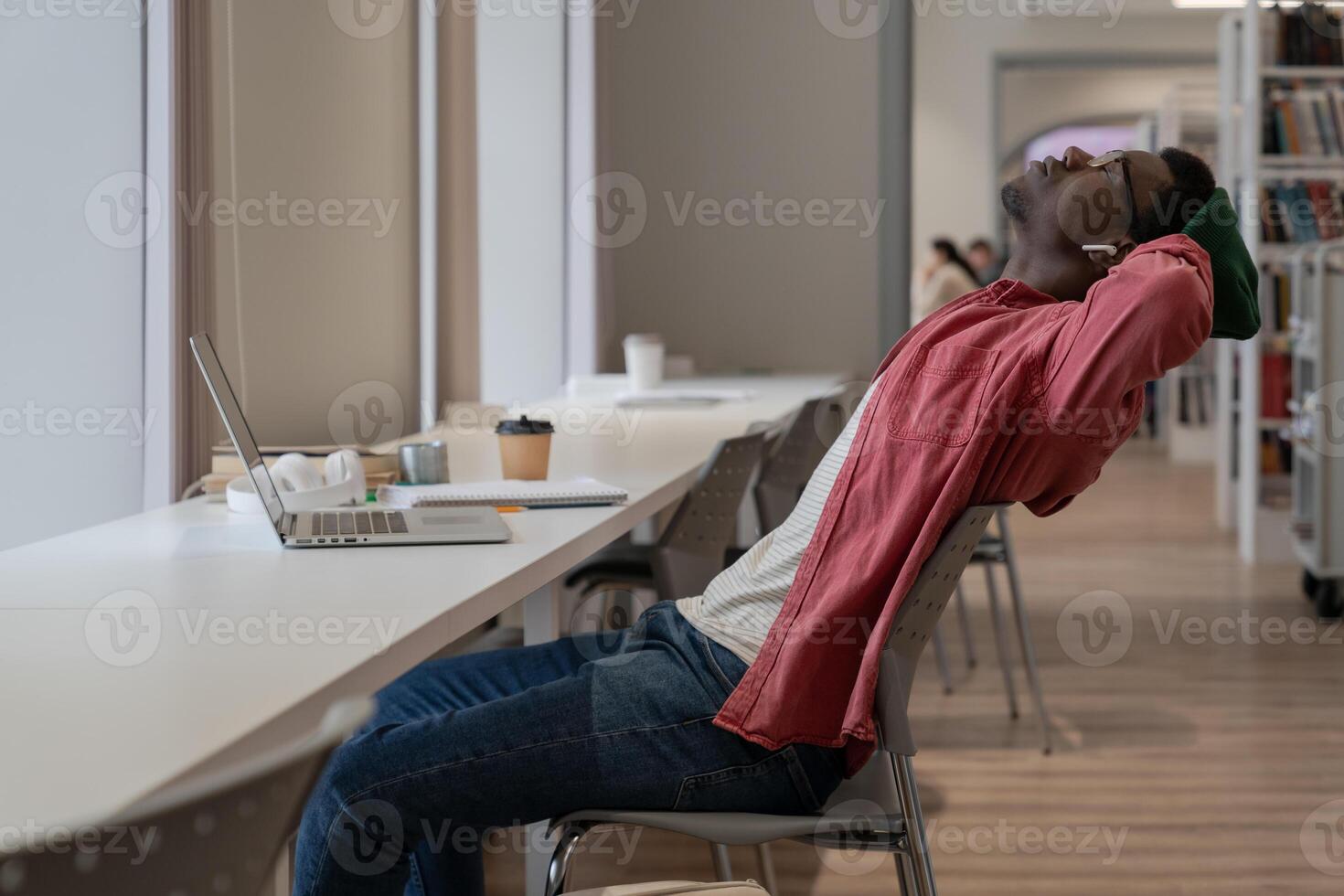 Exhausted black guy student resting in library, taking break during online learning photo