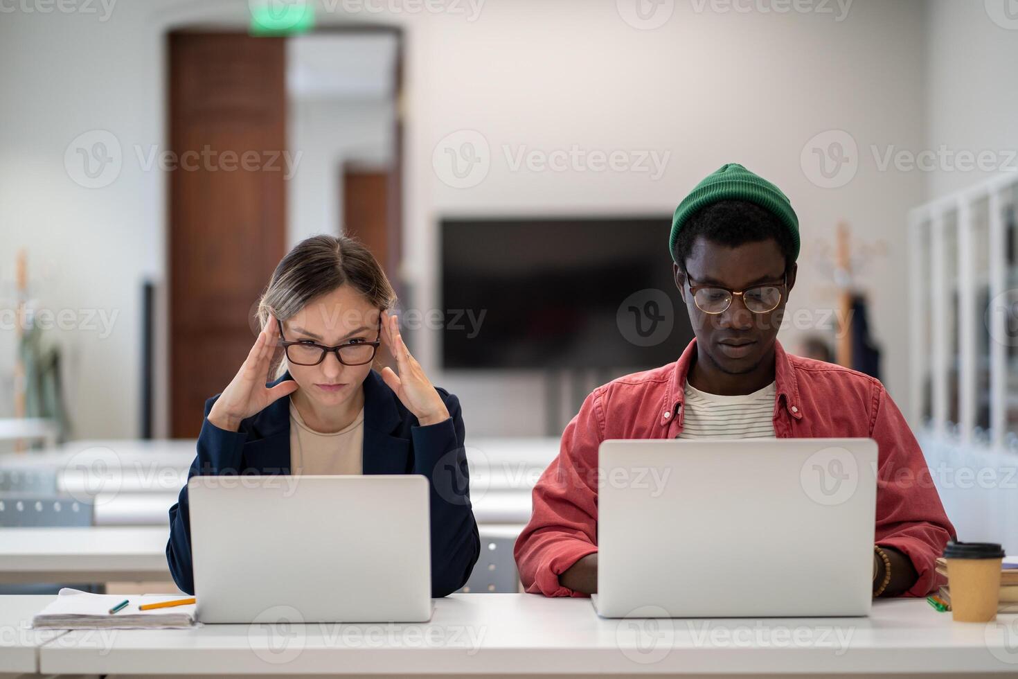 Concentrated serious students learning sitting in desktop in college lecture classroom with laptops. photo
