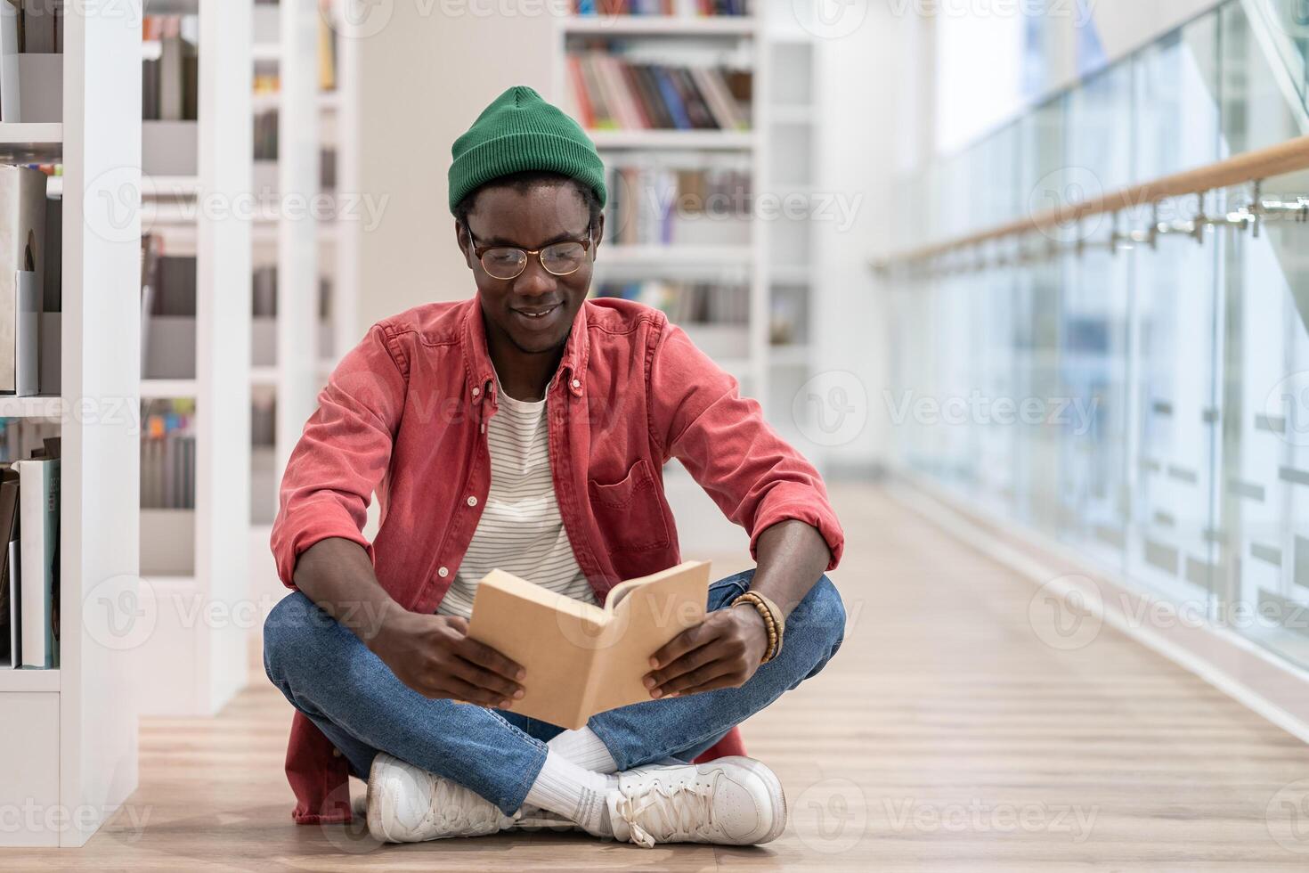 Focused African American guy preparing materials for upcoming lecture reading book in university photo