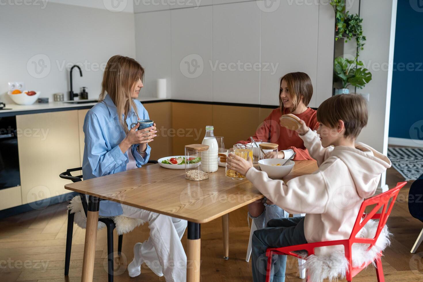 Happy family of three mother and kids have breakfast together at home photo