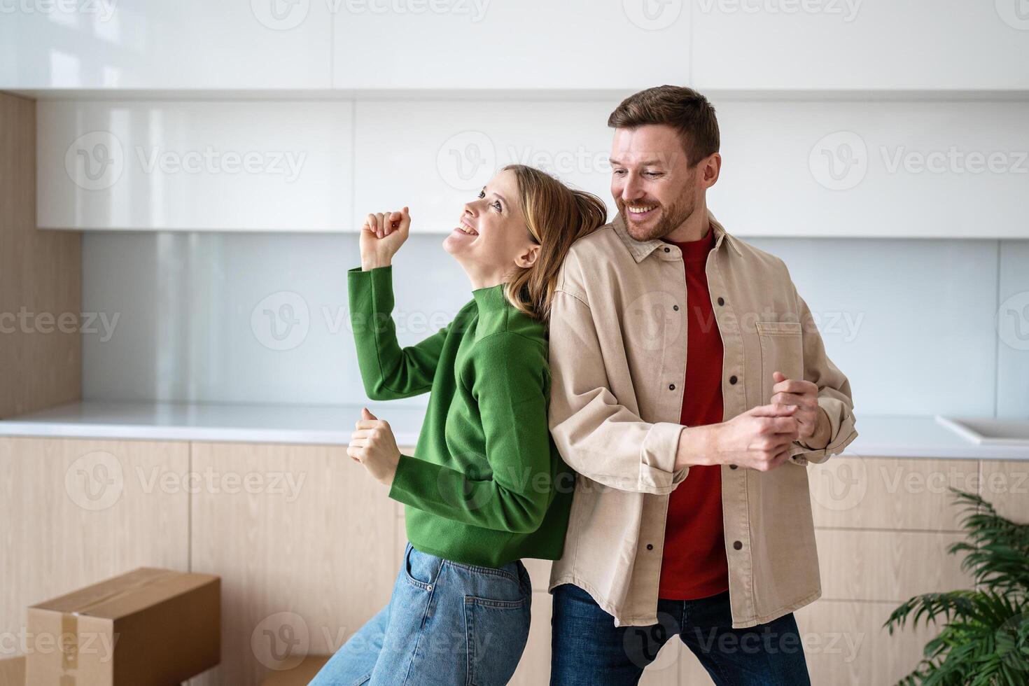 Cheerful married couple happy on moving day dancing together with cardboard boxes at new family home photo