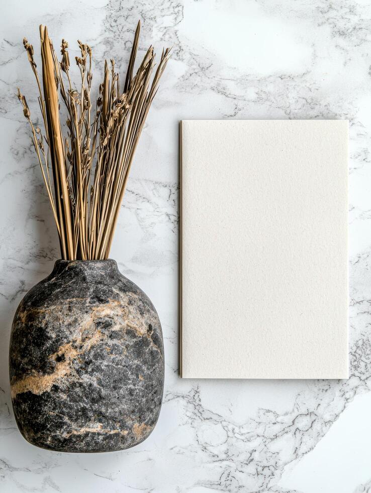 Blank notepad mockup with dried flowers in a vase on a marble background photo