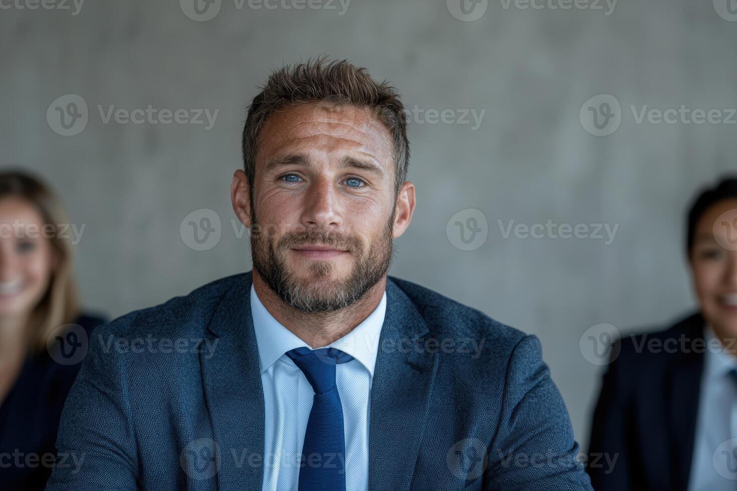 a man in a suit and tie sitting in front of his colleagues photo