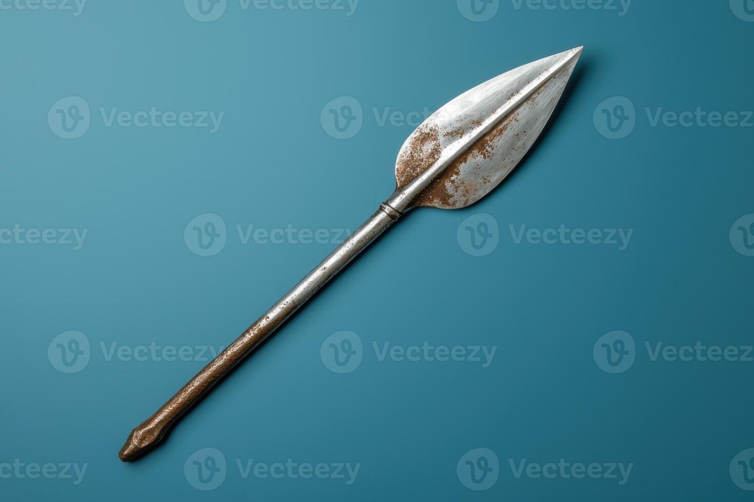 Rusty metal spearhead on a blue background photo