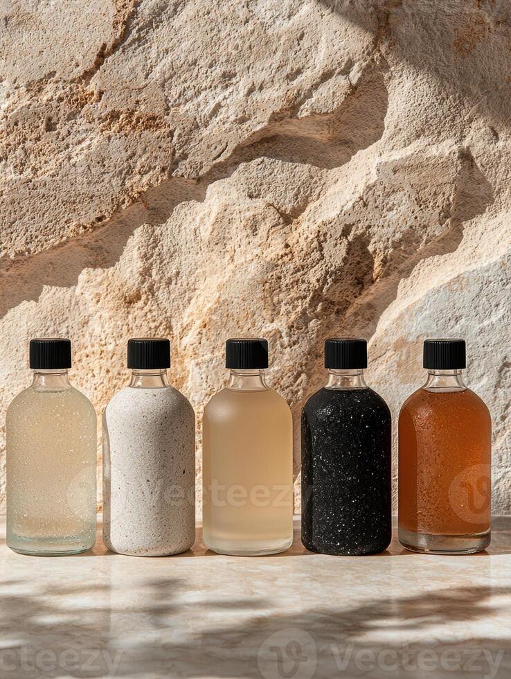 Five bottles of essential oil on a marble surface against a stone wall background photo