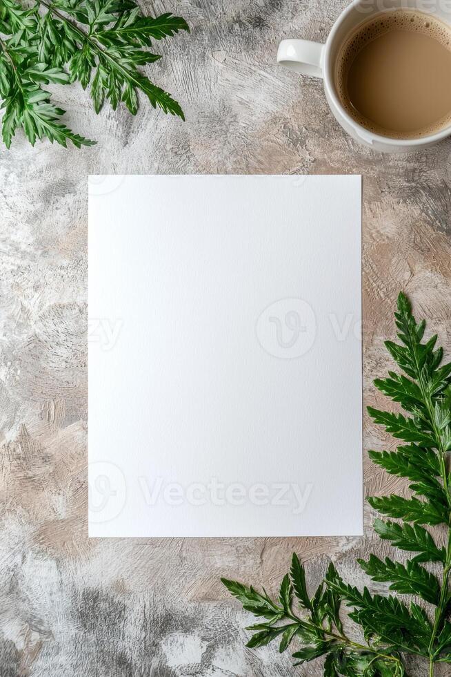 Blank paper mockup surrounded by green leaves and a cup of coffee on a textured background photo