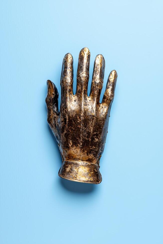 Antique medieval knights metal glove on blue background photo