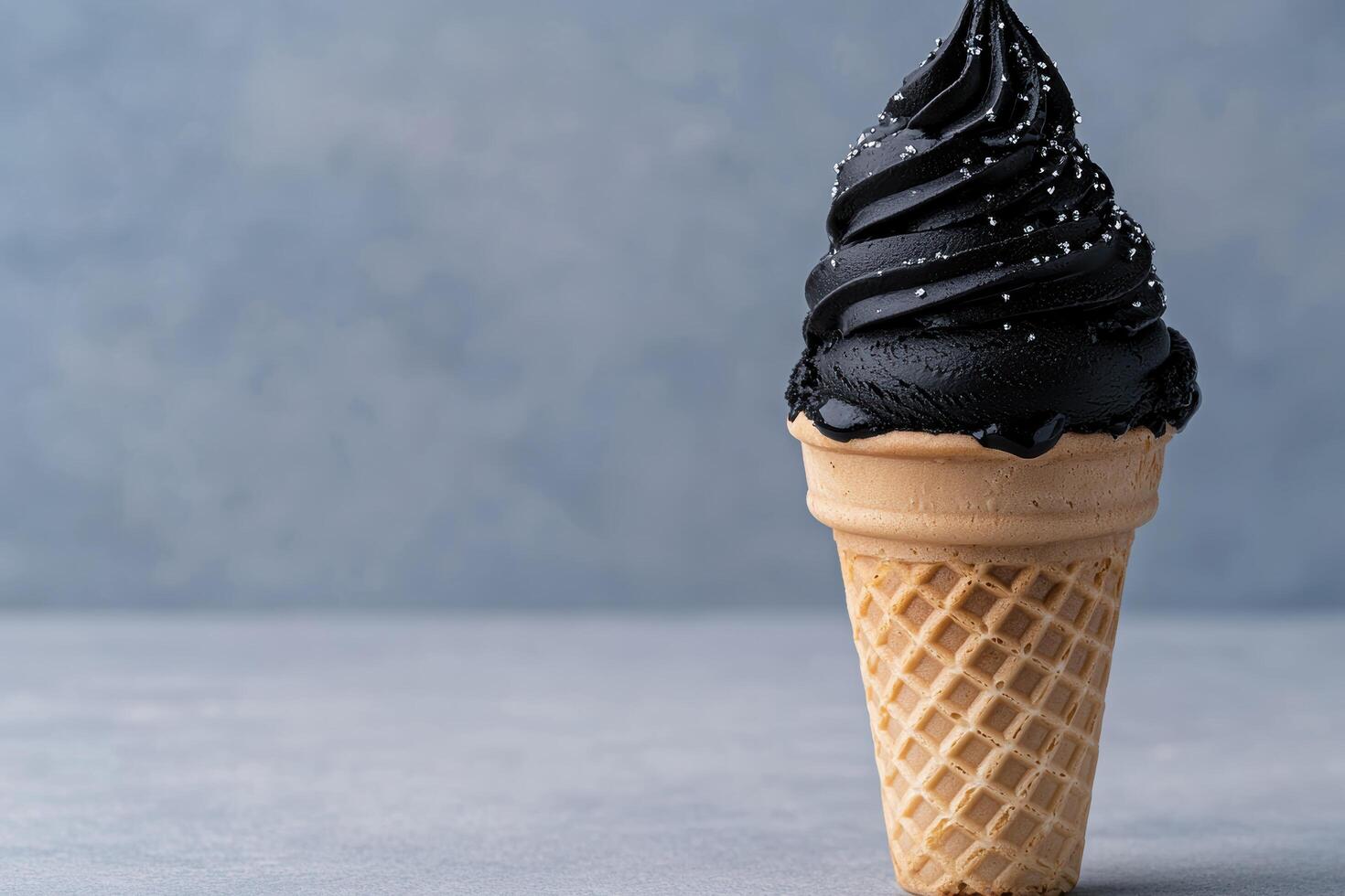 Black ice cream cone with silver sprinkles on a gray background photo
