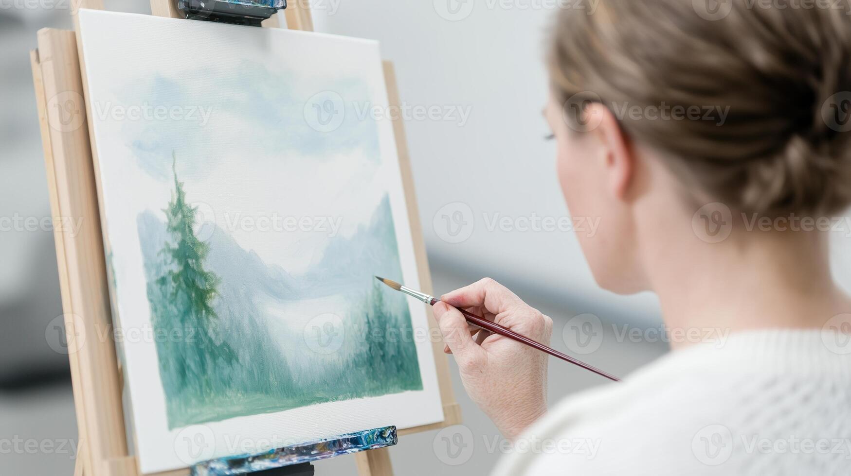 Realistic Painting of Woman Creating Scenic Landscape with Cerebral Palsy Art Style Featuring Mountains and Trees on Canvas photo