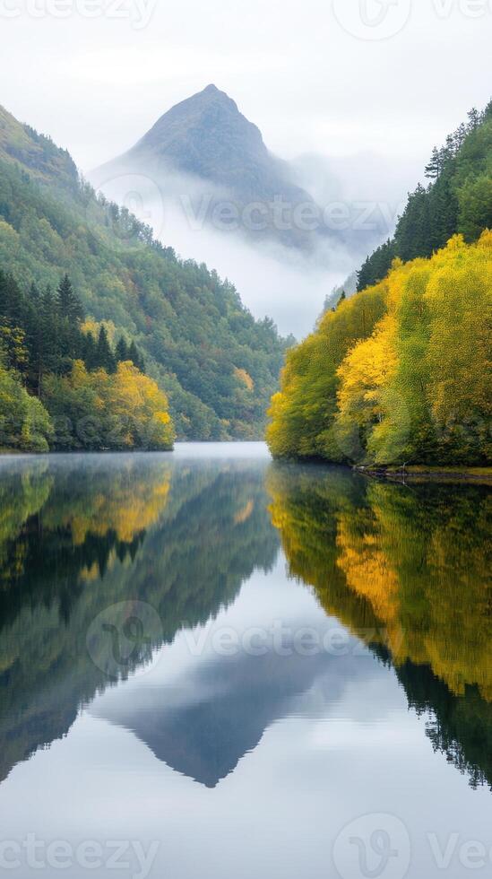 Misty Morning Lake Surrounded by Forest and Mountain Reflection in Autumn with Colorful Foliage and Serene Atmosphere photo
