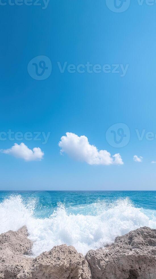 Slow Motion Waves Crashing on Huge Stones Under Clear Blue Sky with Fluffy White Clouds in Summer Beach Scene photo