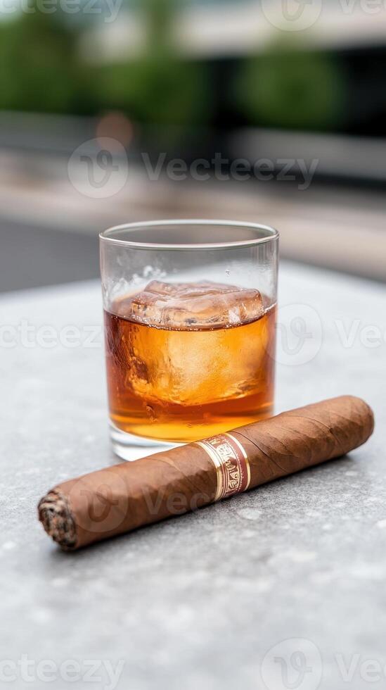 Whiskey Tumbler with Ice and Cuban Cigar on Outdoor Table Surface, Highlighting Luxurious Leisure in Natural Light Photography and Premium Lifestyle Theme photo