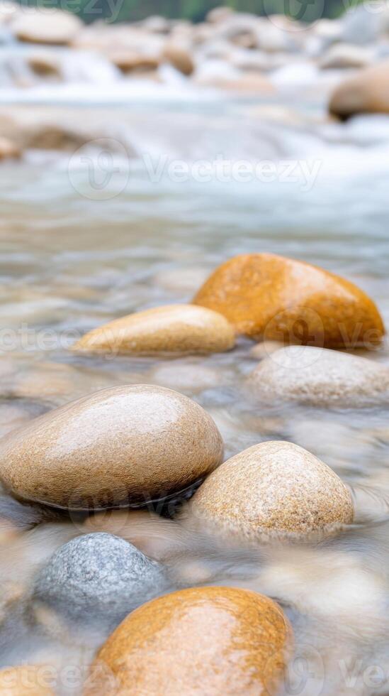 Vertical View of a Streaming River Over Smooth Stones in Natural Setting, Showcasing Serenity and Calmness, Perfect for Nature Lovers and Landscape Photography Enthusiasts photo