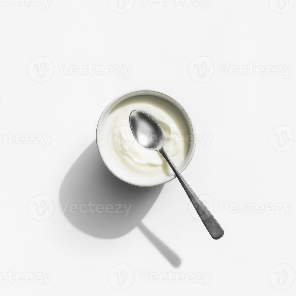 Bowl of creamy yogurt with a silver spoon resting on top illuminated by soft light photo