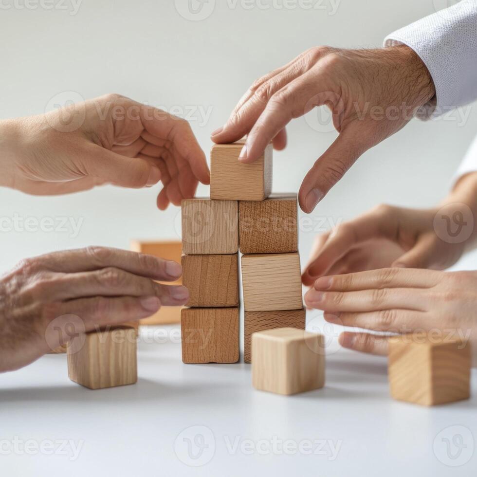 Hands stack wooden blocks together in a collaborative building activity at a light workspace during daytime photo