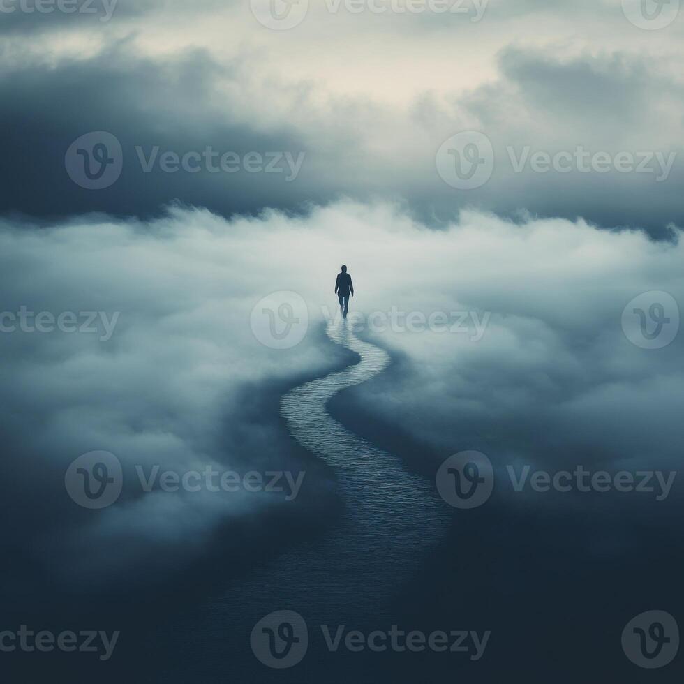 Lonely figure walking along a winding path in the misty clouds at dusk photo