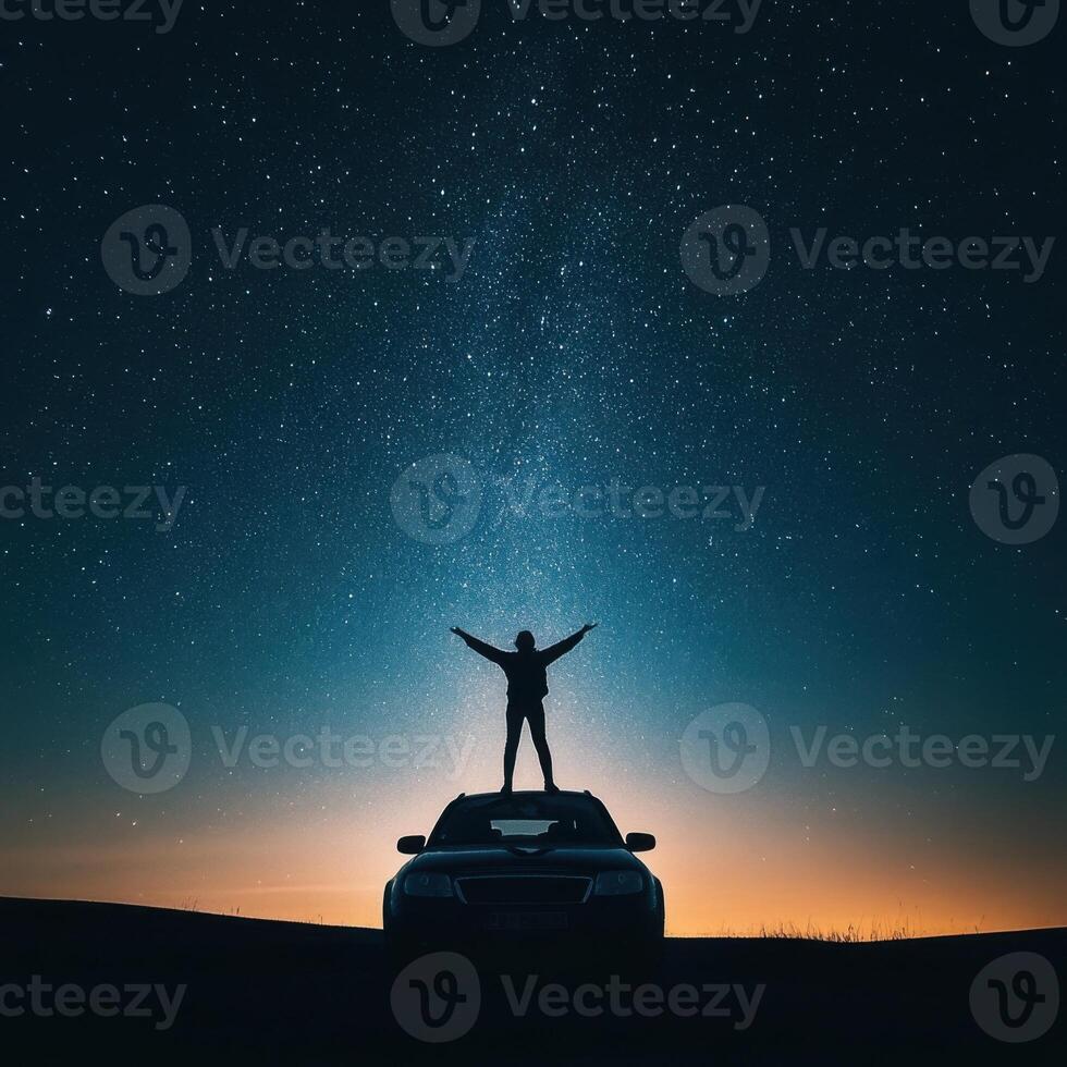 Person stands on car roof under a dazzling starry sky at twilight in a serene outdoor setting photo