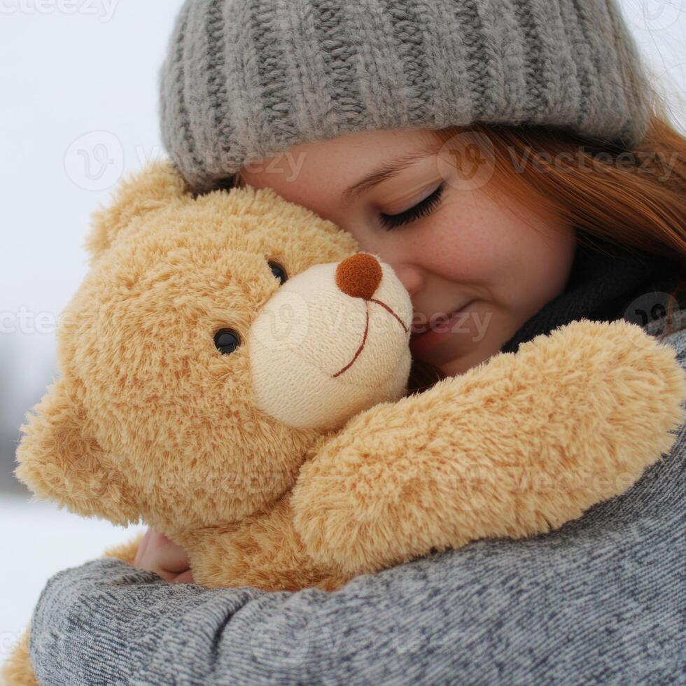 Young girl hugging a teddy bear while enjoying a snowy day outdoors near a serene winter landscape photo