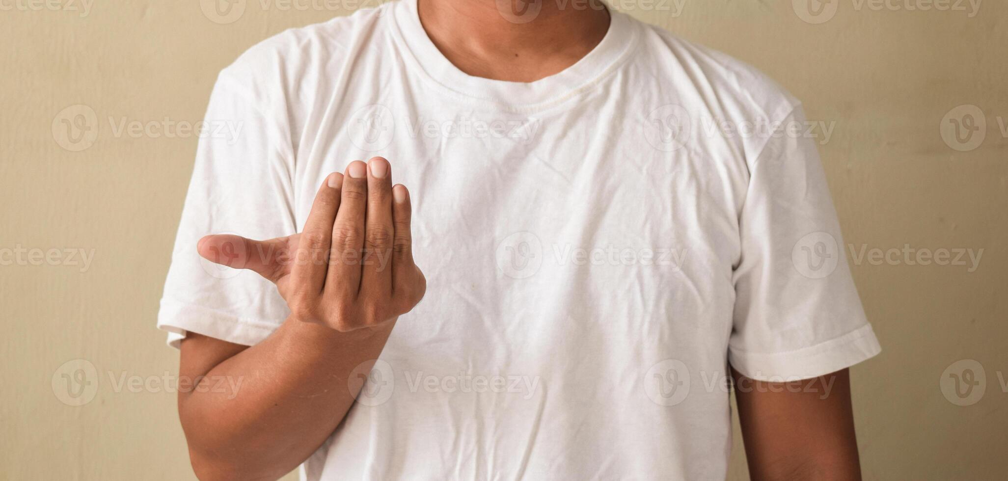 Young man with nude manicure raising hand showing word your sign language photo