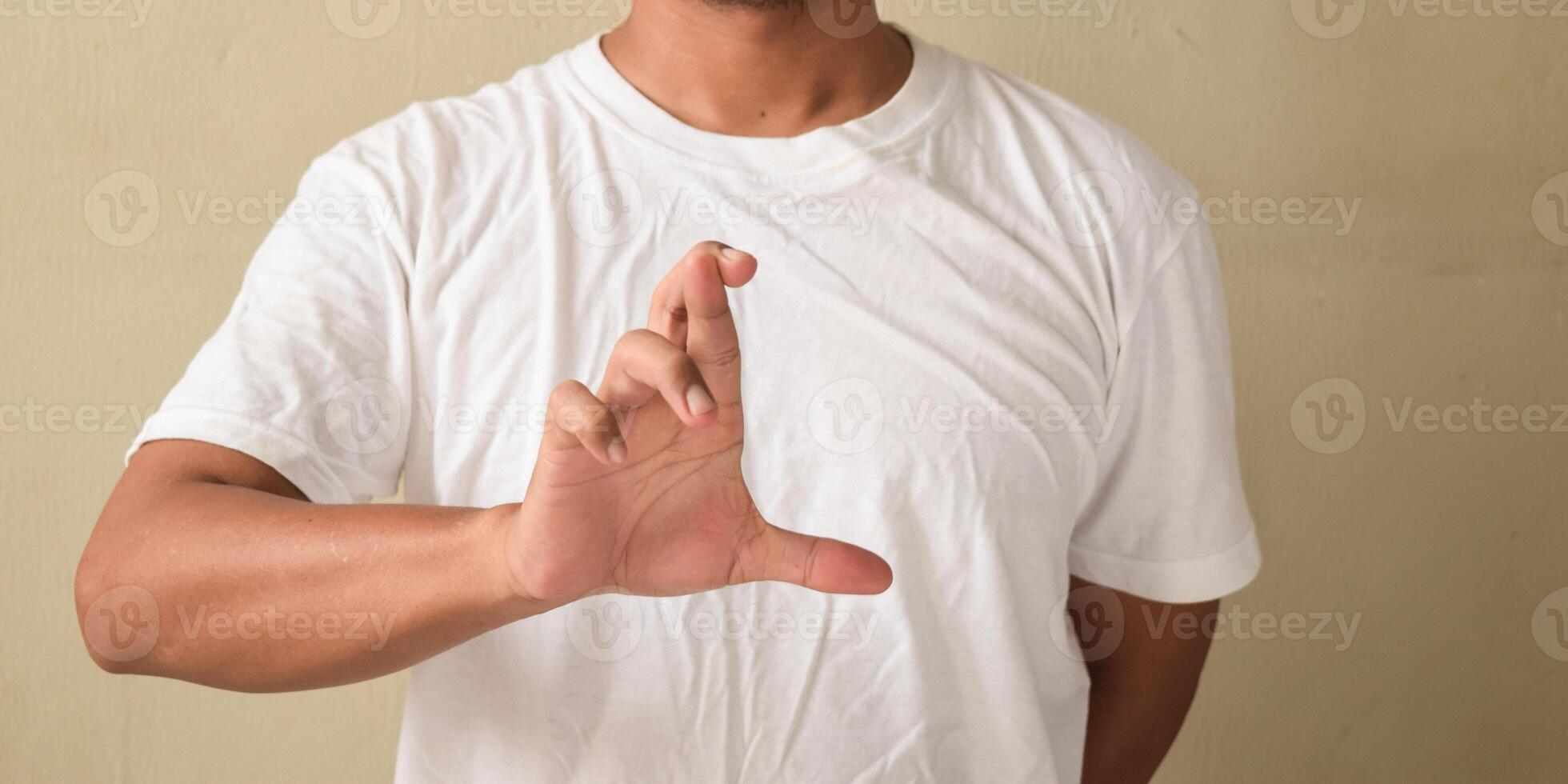 Young man showing crossed finger gesture in sign language photo