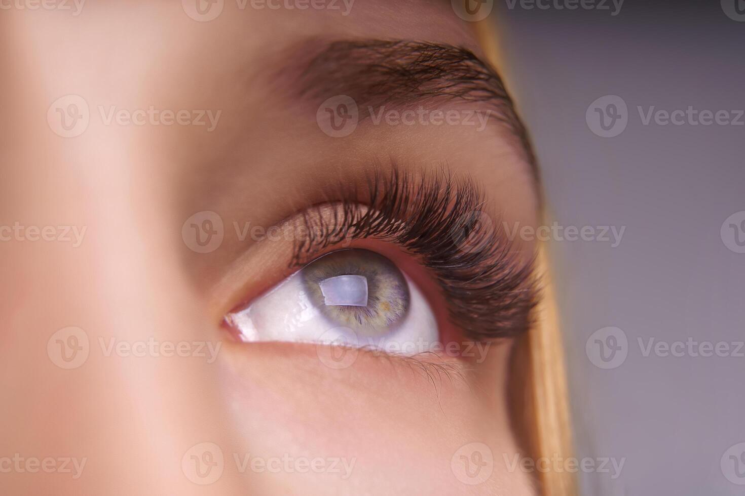 Eyelash Extension Procedure. Woman Eye with Long Eyelashes. Close up, selective focus. photo