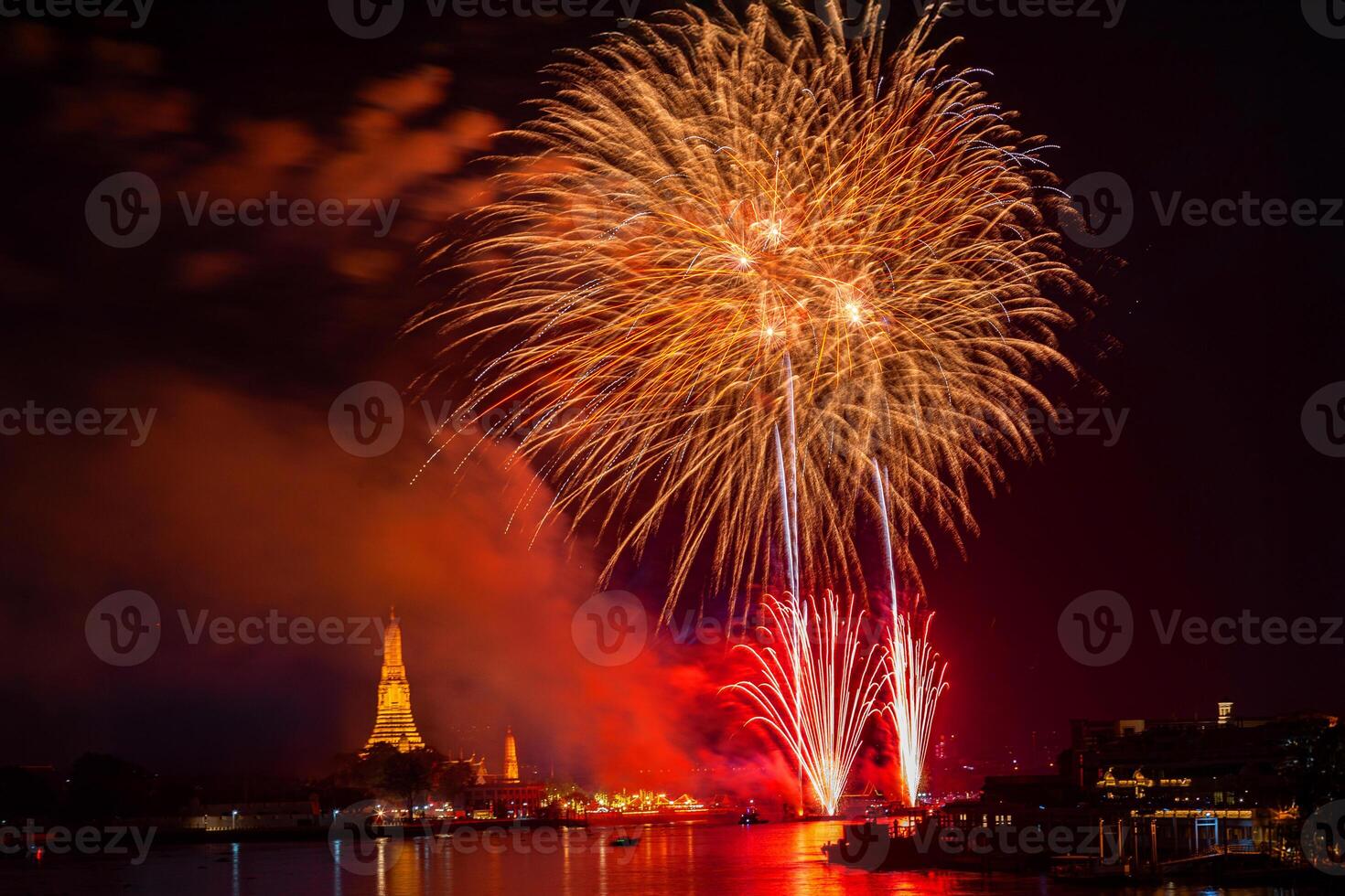 Buddhist temple Wat Arun Ratchawararam Ratchaworawihan famous tourist attraction with beautiful lights and fireworks in the middle of river during New Year festival at night in Bangkok Thailand. photo