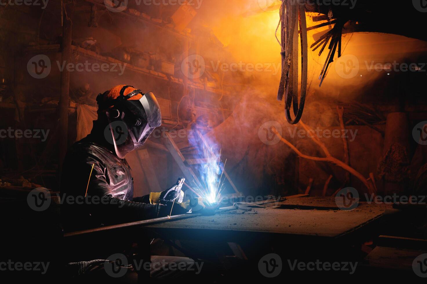 Welder using tool and sparks are generated, welding process in garage, hands with tool in protective clothing and helmet, hobby for adults photo