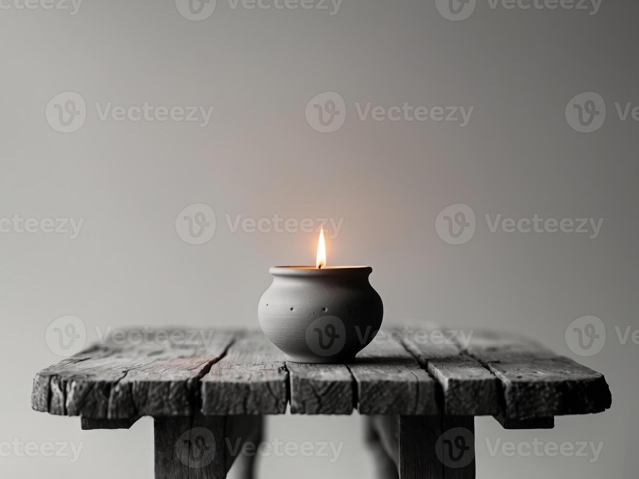 Elegant Clay Pot Candle with Flickering Flame on Rustic Wooden Table Surface. photo