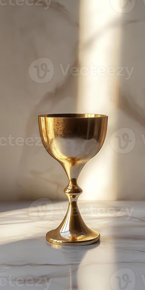 A gold cup sits on a marble countertop, reflecting the light from a window photo