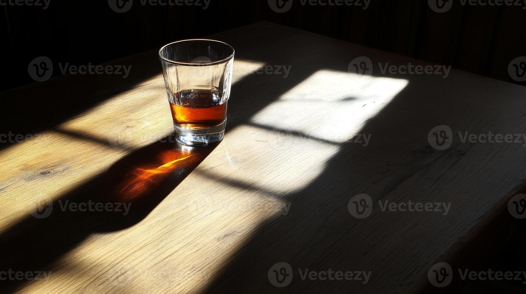A glass of liquor is sitting on a wooden table photo