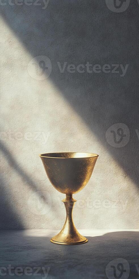 A gold cup sits on a grey wall, with a light shining on it photo