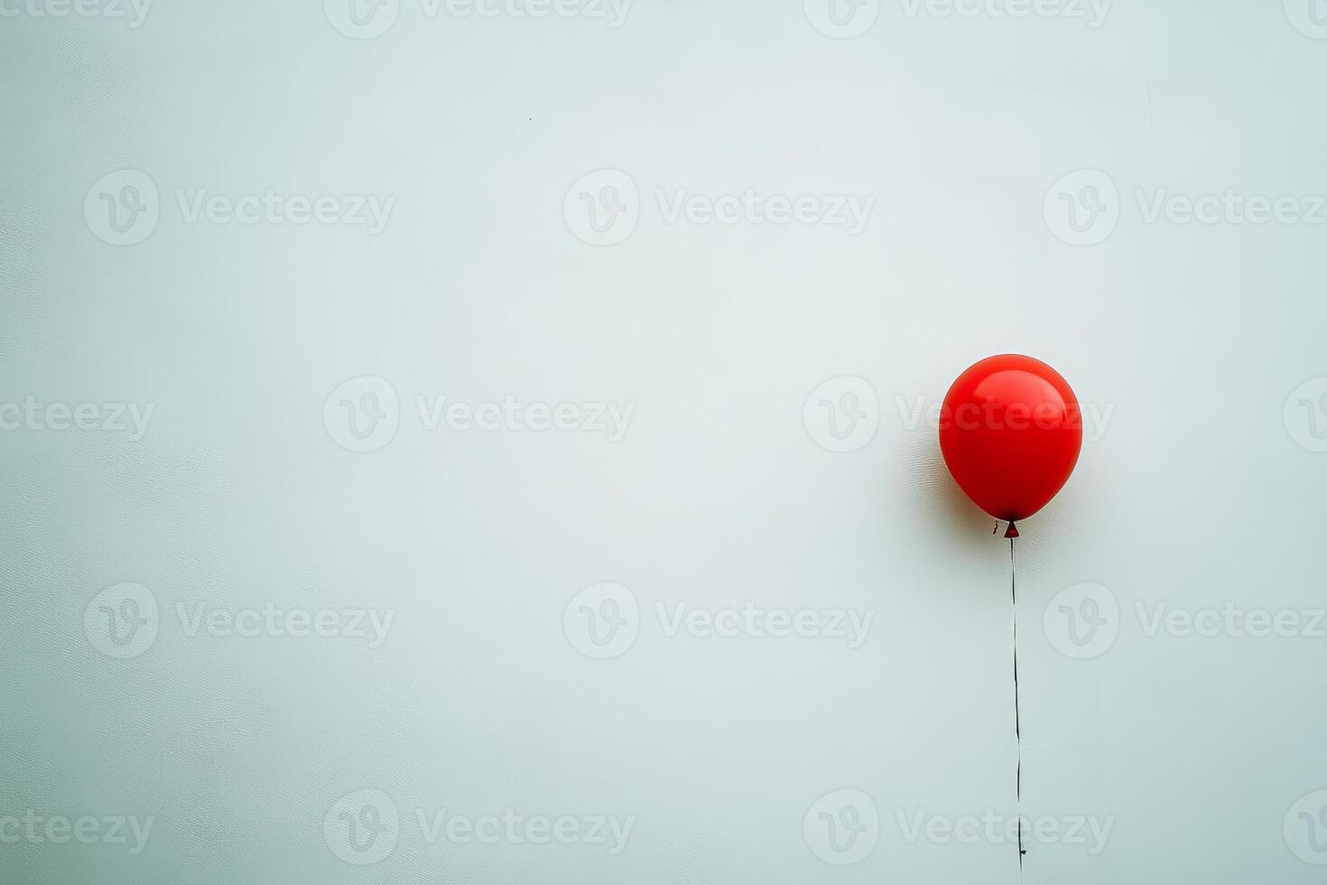 Minimalist Image of a Single Red Balloon Against a Plain White Background photo