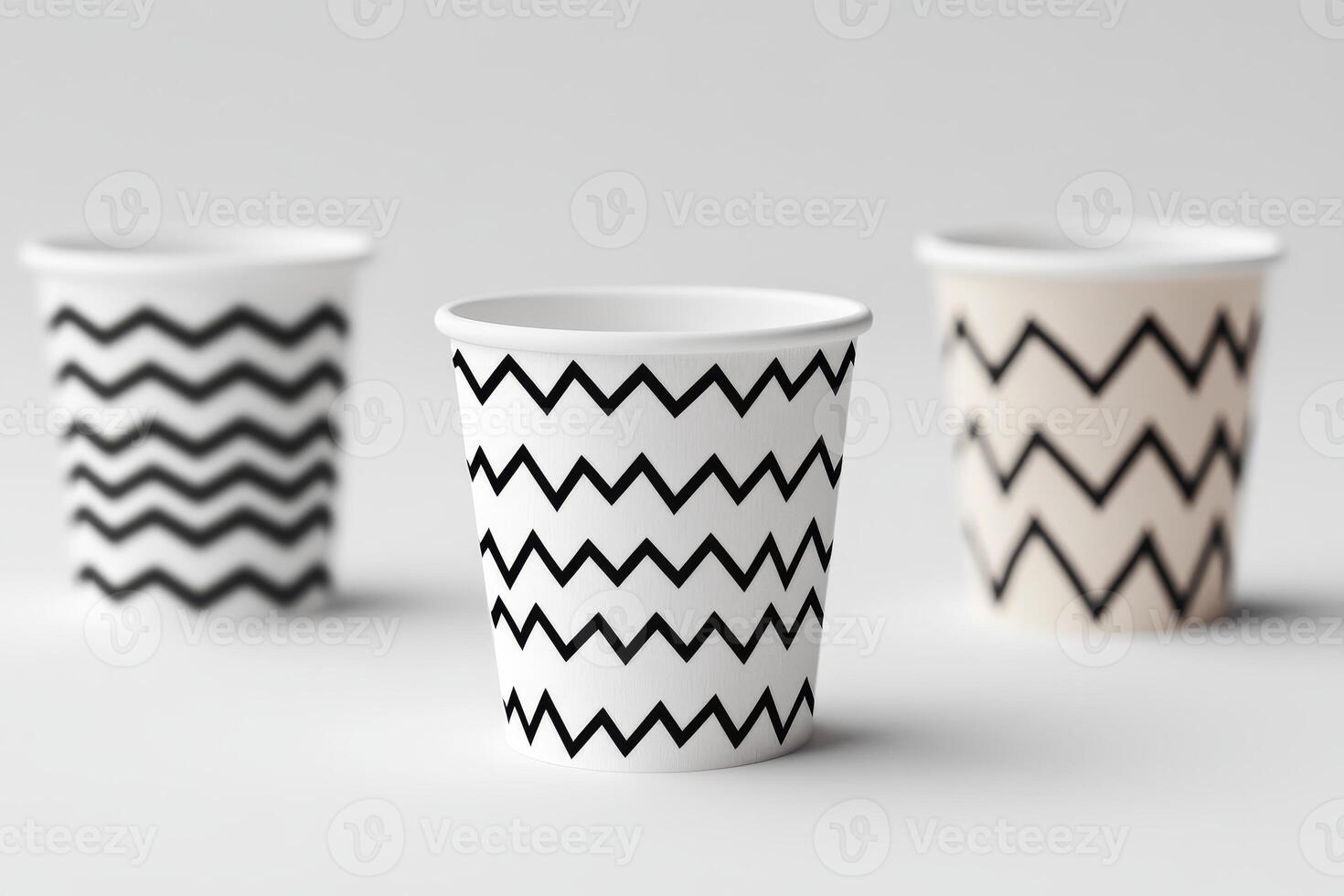 Three cups with zigzag patterns on them. The cups are white and black. The cups are lined up next to each other photo