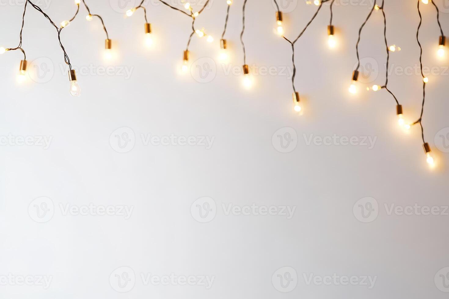 A string of lights is hanging from the ceiling. The lights are on and are evenly spaced. The lights are on a white background photo
