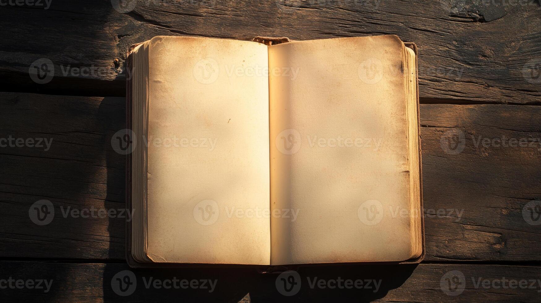 A book is open on a wooden table. The book is old and has a worn look to it. The pages are yellowed and the cover is frayed. The book is open to a page with no writing on it photo